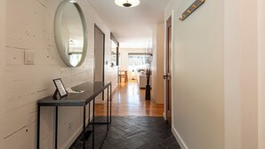 A hallway with a black herringbone floor, a round mirror on the left, and a reception desk with a sign. - Hulen Way Home - Newly Remodeled Home with Trails Right Out the Front Door (Ketchum)