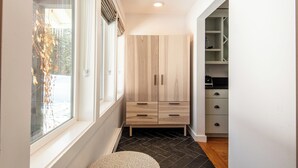 A hallway with a window, a light wood cabinet, a black tiled floor, and a white wall. - Hulen Way Home - Newly Remodeled Home with Trails Right Out the Front Door (Ketchum)