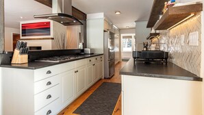 A modern kitchen with white cabinets, stainless steel appliances, and a black countertop. - Hulen Way Home - Newly Remodeled Home with Trails Right Out the Front Door (Ketchum)