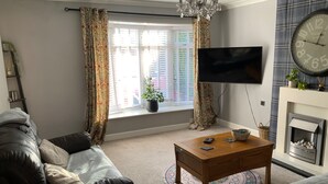 Ett vardagsrum med en soffa, ett soffbord, en tv och en öppen spis.