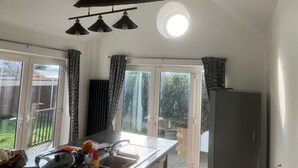 Eine Küche mit einem großen Fenster, einer Hängelampe und einem Kühlschrank.