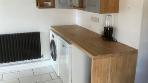 Eine kompakte Küche mit Einbauwaschmaschine, Kaffeemaschine und Heizkörper.