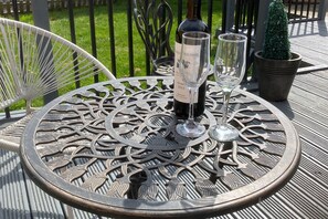 A round metal table with a decorative metal chair, a wine bottle, and two wine glasses on it. - Wall Heath Retreat - Period 3 Bedroom Cottage (Kingswinford)