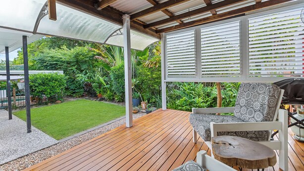A covered patio with wooden flooring, white furniture, and a view of a lush garden. - Tropical Family Retreat with Pool and Garden (Machans Beach)