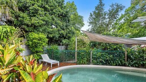 A swimming pool surrounded by lush greenery, a white lounge chair, and a shaded area. - Tropical Family Retreat with Pool and Garden (Machans Beach)