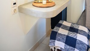 A bathroom with a round mirror, a small sink with a wooden tray, a checkered towel, and a blue curtain. - Cozy Studio 2 (Malia)