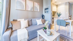 A modern living room with a grey sofa, white coffee table, and a dining area with a white table and chairs.