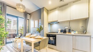 A modern kitchen with a dining area, featuring a large window, a dining table with chairs, and a built-in oven.