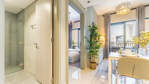 A modern hotel room with a sliding door leading to a balcony, a dining area with a table set for two, and a potted plant.