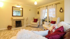 A living room with a fireplace, two armchairs, a sofa, and a fluffy white rug. - Crown Farm (Wisbech)