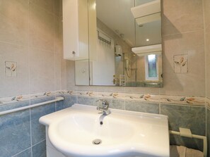 A bathroom with a white sink, a mirror, and a shower area.