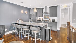 A modern kitchen with a large island, bar stools, and stainless steel appliances. - Close to DT Game Garage Bar Large Living Room (Nashville)