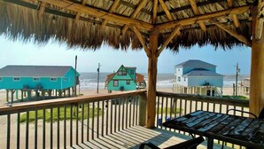 A beach house with a thatched roof and wooden deck, overlooking the ocean. - La Palapa whole house at pedestrian beach! Surfside Beach Texas! (Freeport)