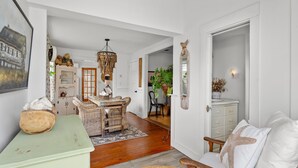 A cozy living room with a wooden coffee table, wicker chairs, a white sofa with a starfish pillow, and a green sideboard. - Cape Cod Bungalow Walk to Beach Firepit (Yarmouth)