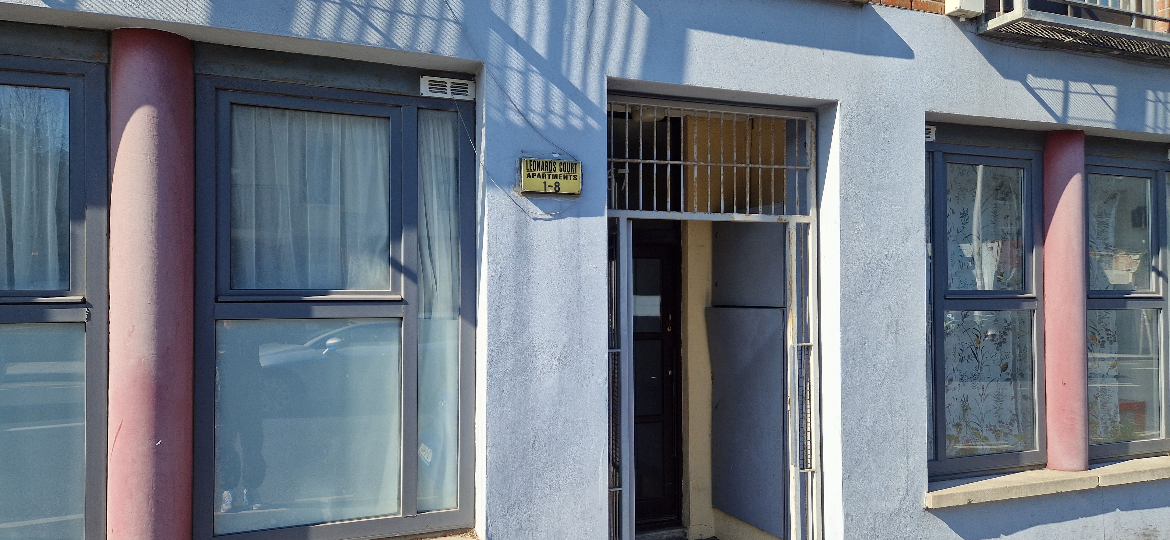 A building with a sign indicating 'Leonards Court Apartments 1-8'.
