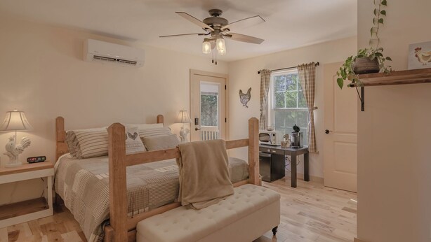 A bedroom with a wooden bed, a bedside table with a lamp, a ceiling fan, and a window with curtains. - The Inn at Beulah Farm - The Coop (Whitley City)