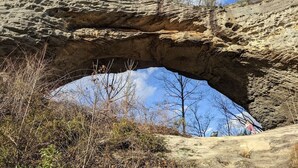 A natural rock arch formation with sparse vegetation and a clear sky. - The Inn at Beulah Farm - The Coop (Whitley City)