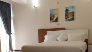 Une chambre d’hôtel avec un grand lit, un plancher en bois et deux tableaux accrochés au mur.