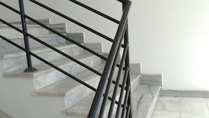 Un escalier avec une rampe en métal noir et des marches en marbre.