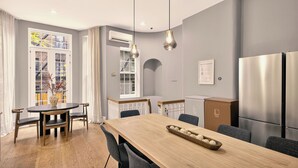 A modern kitchen with a wooden dining table, two pendant lights, and stainless steel appliances. - Outsite Chelsea - Work, Connect, Explore (New York)