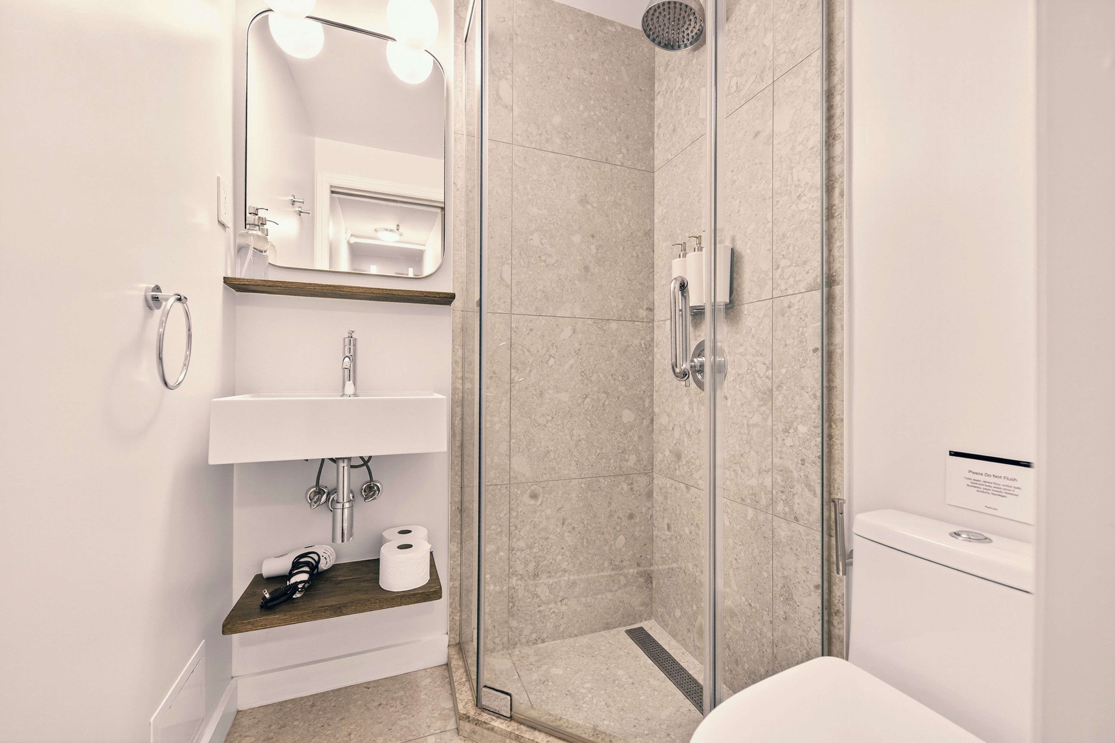 A modern bathroom with a glass-enclosed shower, a sink with a mirror, and a toilet.