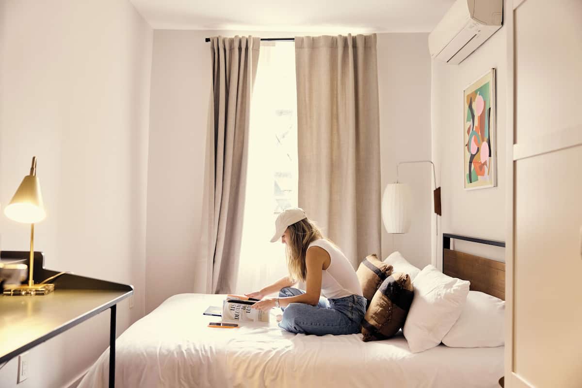 A hotel room with a bed, a desk, and a lamp.