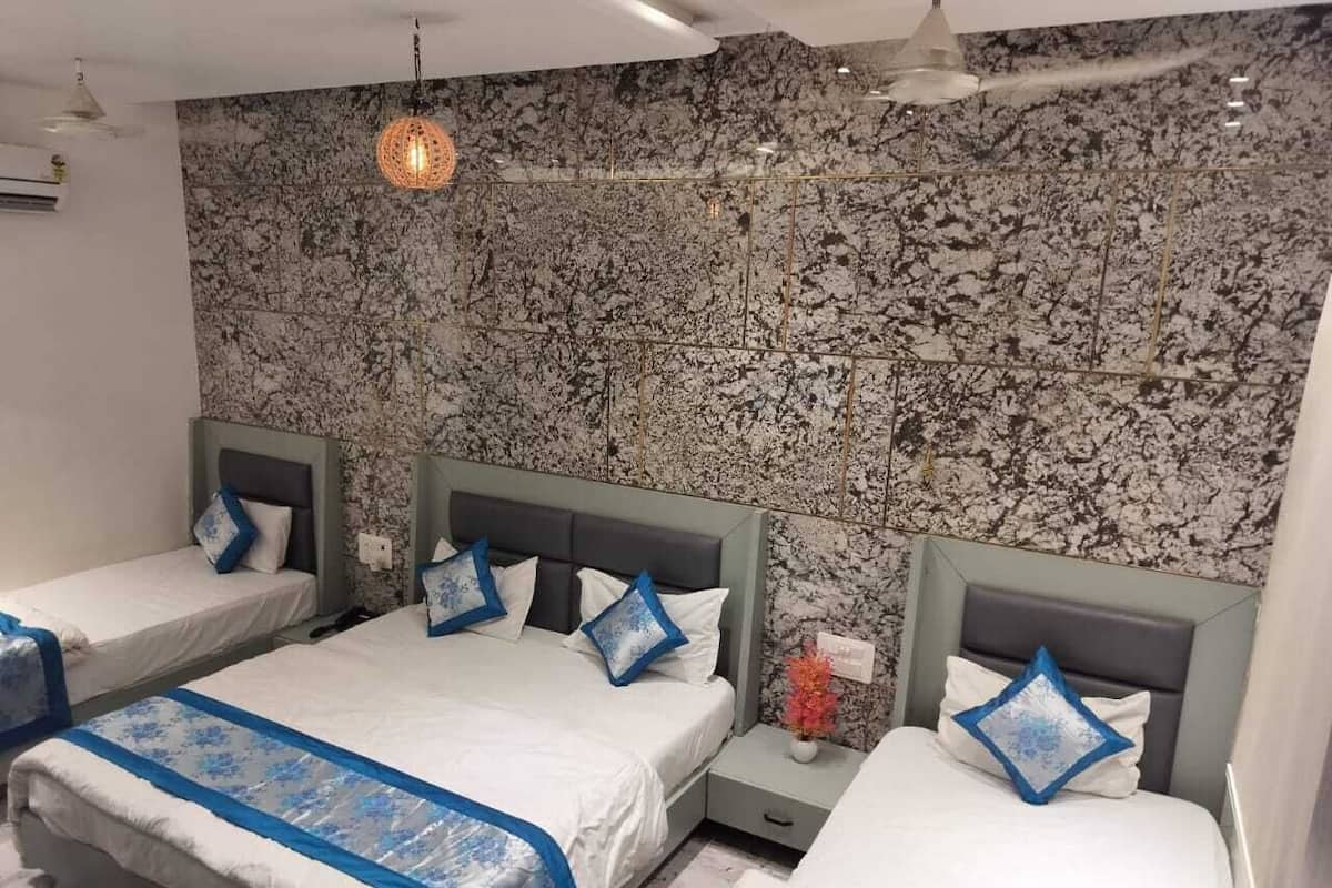 Une chambre d’h ôtel avec trois lits simples, chacun doté d’une tête de lit et d’oreillers assortis.