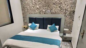 A bed with a blue quilt, two blue pillows, and a white bedspread. - Shri Balaji Dham Hotel (Vrindavan)