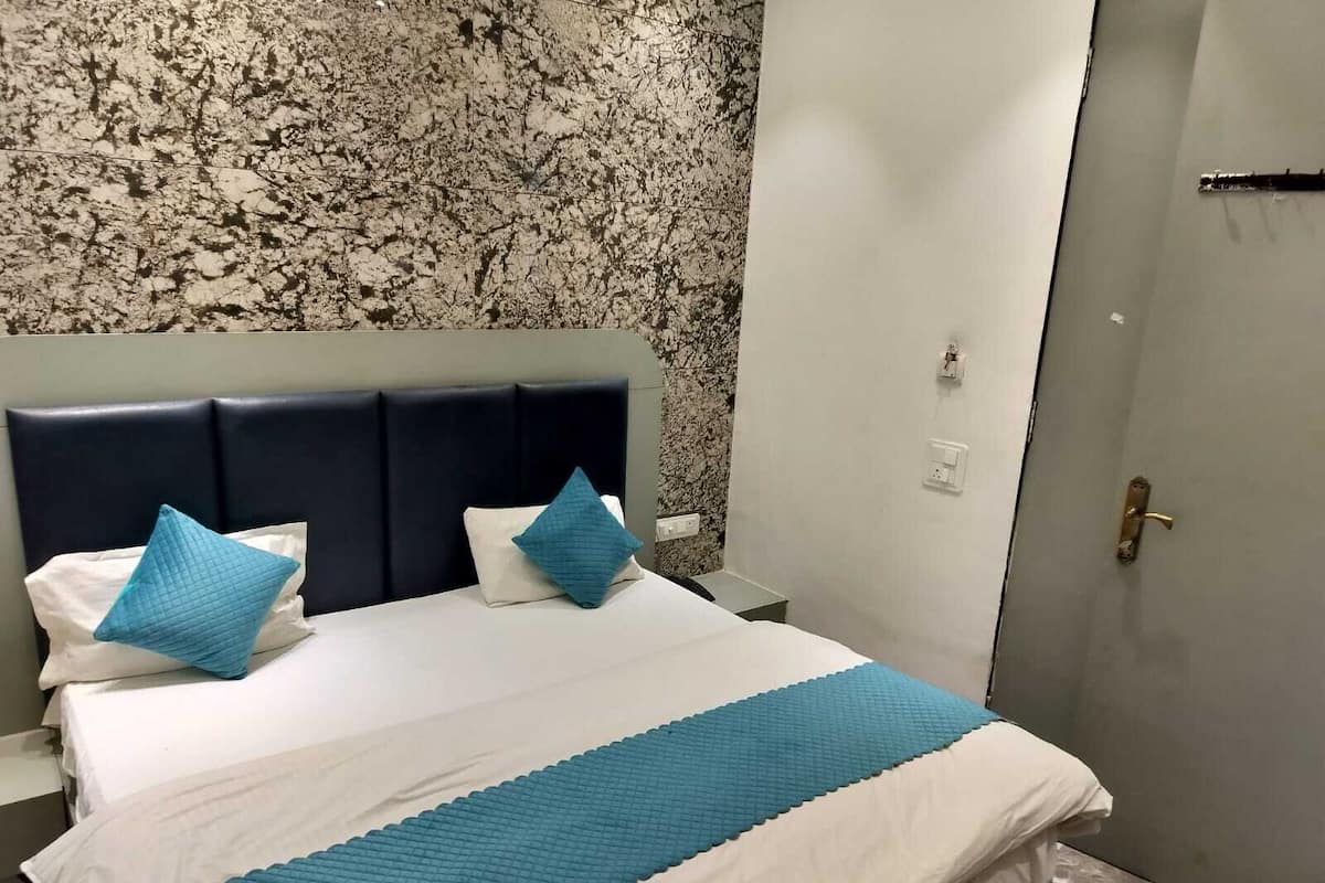 Une chambre d’hôtel avec un lit, une tête de lit et une porte.