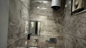 A bathroom with a marble wall, a white sink, a toilet, and a hand dryer. - Shri Balaji Dham Hotel (Vrindavan)