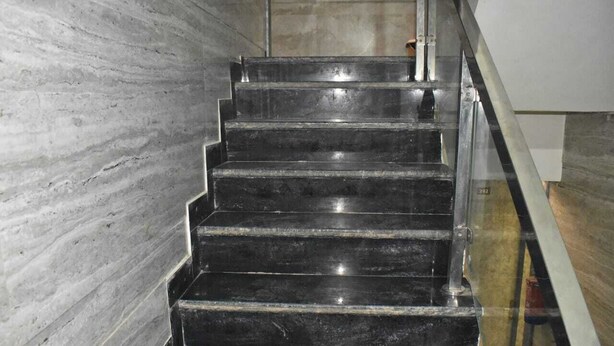 A set of black marble stairs with a glass handrail, leading to a higher floor. - Shri Balaji Dham Hotel (Vrindavan)