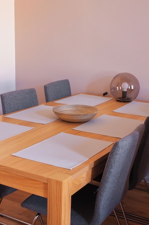 Una mesa de conferencias con seis sillas grises, un cuenco de madera y una lámpara de cristal transparente.