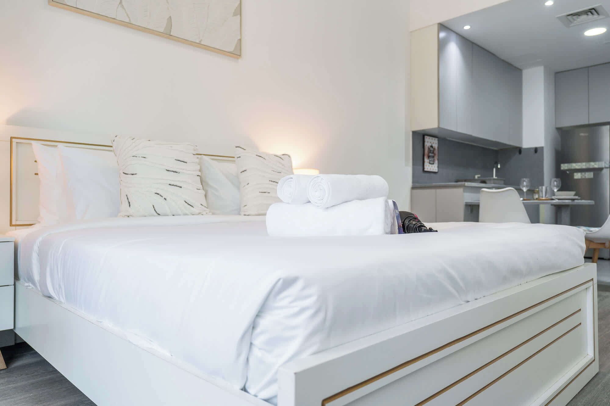 Quarto de hotel moderno com uma cama grande, roupa de cama branca e cama bem arrumada com toalhas.