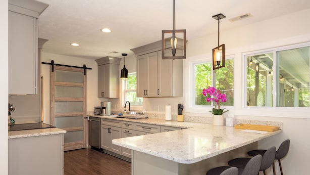 A modern kitchen with a large island, bar stools, and pendant lighting.