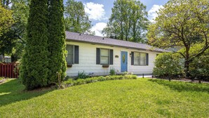 A single-story house with a front yard, a blue door, and a small garden area.