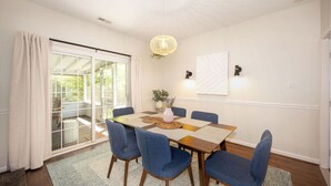 A dining area with a wooden table, blue chairs, a woven placemat, and a hanging light fixture.
