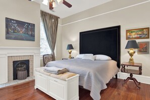 A bedroom with a large bed, a fireplace, and two bedside tables with lamps.