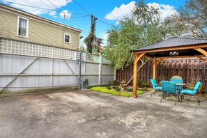 A backyard with a patio area, a wooden fence, and a covered seating area.
