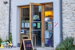 A restaurant entrance with a wooden door, glass windows, and various signs and notices. - La Grange à Gaby (Engins)