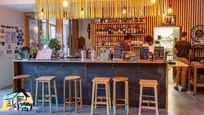 A bar with wooden stools, a bar counter, and hanging light fixtures. - La Grange à Gaby (Engins)