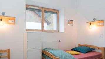 A bedroom with a bed, a radiator, a window, and wall-mounted lights.