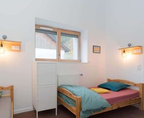 A bedroom with a bed, a radiator, a window, and wall-mounted lights. - La Grange à Gaby (Engins)