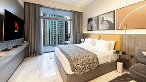 A modern hotel room with a large bed, a flat-screen TV, a balcony with a city view, and artwork on the walls. - Studio with City Views & Modern Amenities in MAG 318, Business Bay (Business Bay)
