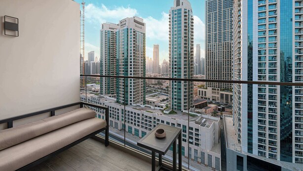 A balcony with a view of high-rise buildings, a bench, and a small table with a bowl. - Studio with City Views & Modern Amenities in MAG 318, Business Bay (Business Bay)