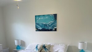 A bedroom with a large bed, white bedding, a blue artwork on the wall, and two bedside tables with lamps. - 1 block to the beach, perfect! (Cocoa Beach)