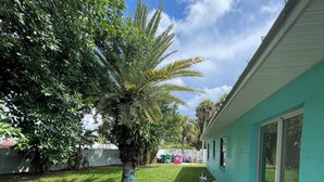 A residential backyard with a concrete pathway, potted plants, a bicycle, and a teal house. - 1 block to the beach, perfect! (Cocoa Beach)