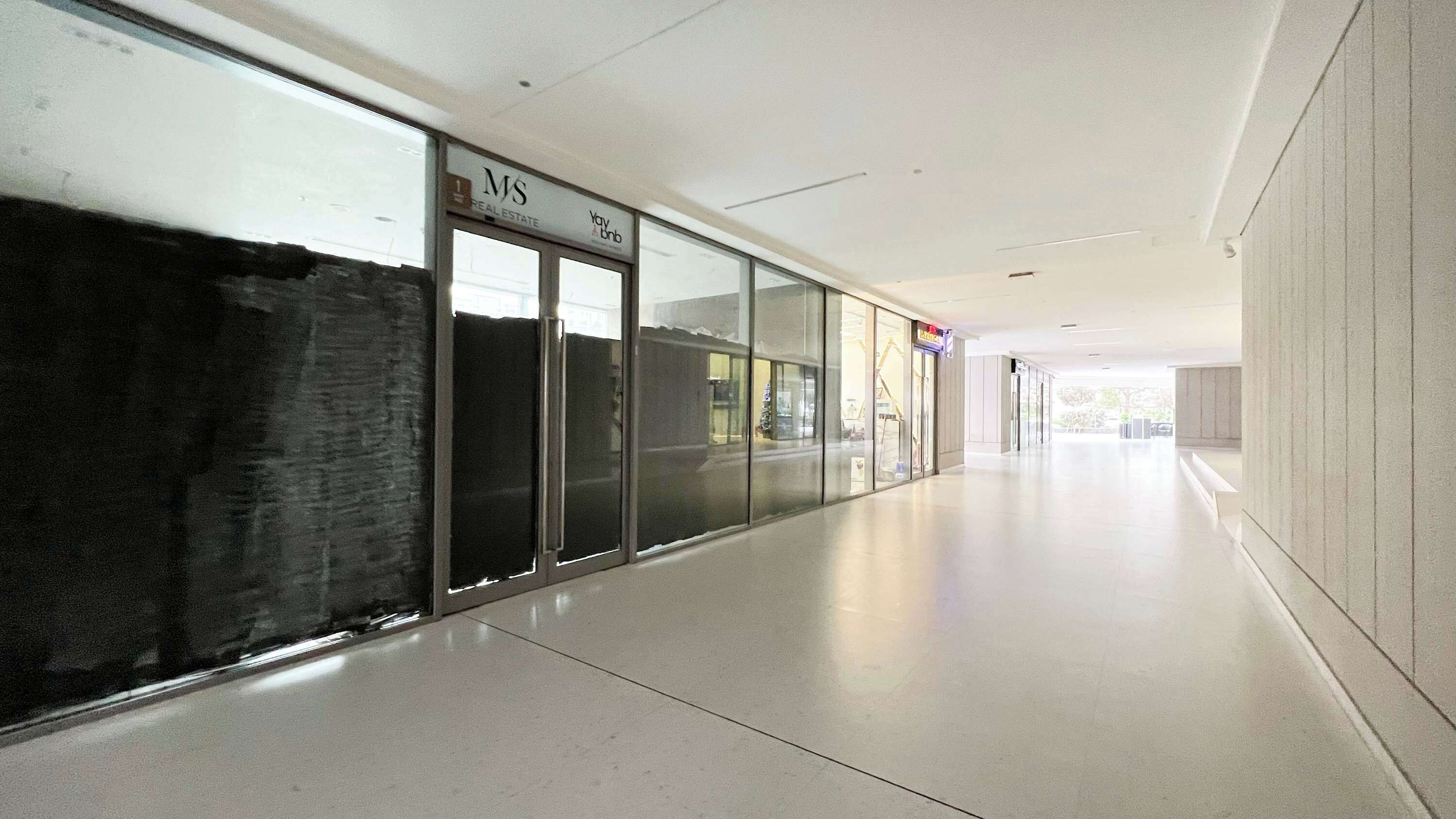 A corridor with glass doors, a sign for 'MS Real Estate', and a 'Yougo' sign.
