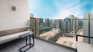Ein Balkon mit einer Couch und einem Tisch, mit Blick auf eine Stadtlandschaft mit modernen Gebäuden und einem Fluss.