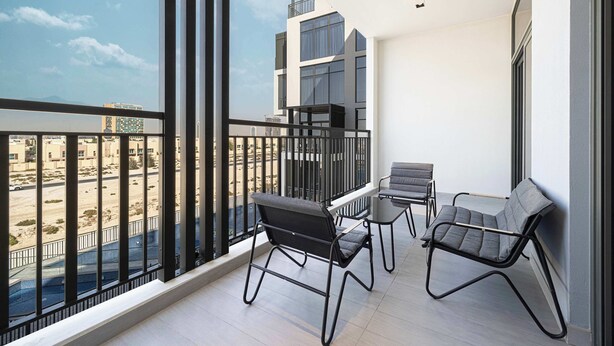 Ein Balkon mit Blick auf eine Wüstenlandschaft, mit zwei Stühlen und einem kleinen Tisch.