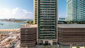 Un edificio alto con facciata curva, ampie finestre e vista sul mare.
